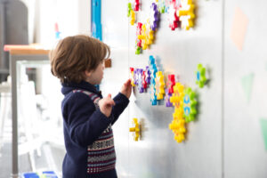 Kid playing with magnetic gears on a magnet wall