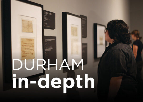 Person looking at framed documents on a grey wall.